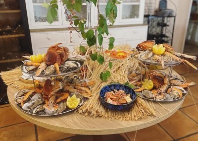 Un buffet de fruits de mer sur une table en bois, décoré de citrons et de feuilles, dans une salle lumineuse.