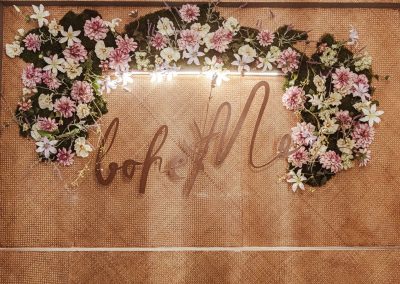 Signe floral élégant avec des fleurs roses et blanches sur un fond en toile, illuminé par une lumière douce, crée une atmosphère chaleureuse.