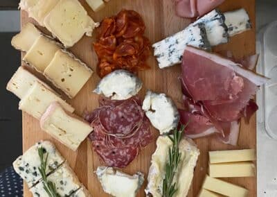 Assortiment de fromages et charcuteries sur une planche. Cornichons et oignons en accompagnement. Présentation conviviale pour un apéritif ou un repas léger.