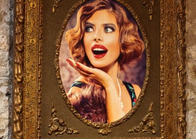 Un portrait encadré d'une personne avec une expression surprise, accroché à un mur en pierre. Le cadre est richement orné de motifs dorés.