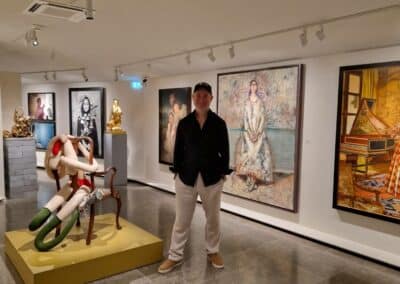 Personne dans une galerie d'art moderne, entourée de peintures et sculptures. L'éclairage met en valeur les œuvres exposées sur les murs.