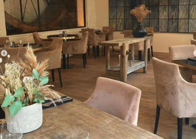 Un restaurant élégant avec des tables en bois, des chaises confortables, et des décorations florales subtiles, créant une atmosphère accueillante et chaleureuse.
