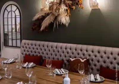 Une salle à manger élégante avec une table en bois, décor automnal et lumières murales, prête pour le dîner. Ambiance chaleureuse et accueillante.