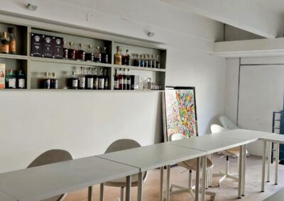 Bright room with bottle-filled shelves, colorful chalkboard and white desks. Window with outside view. Modern, uncluttered atmosphere.