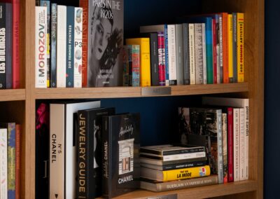 Des étagères en bois remplies de livres sur Paris, la mode et l'art, avec un accent sur les années 1920 et les marques célèbres.
