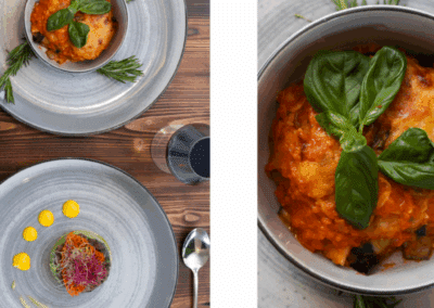 Assiettes avec plats colorés, garnis de feuilles de basilic et romarin. Présentation élégante sur une table en bois, accompagnée d'un verre d'eau.