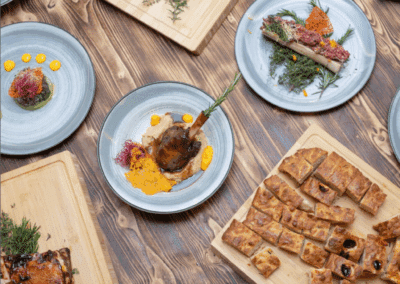 Des plats divers et élaborés sont disposés sur une table en bois, mettant en valeur une cuisine raffinée et créative.