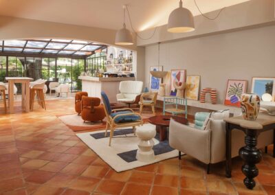 Un salon lumineux et moderne avec mobilier coloré, œuvres d'art sur les murs et grandes baies vitrées donnant sur un jardin verdoyant.